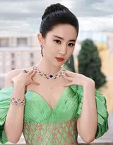 刘亦菲优雅倚靠在雕花石栏边，绿色裙摆如瀑布般倾泻而下，她微微仰首望向远方，侧脸线条精致如古典雕塑，阳光为她的轮廓镀上一层金色光晕