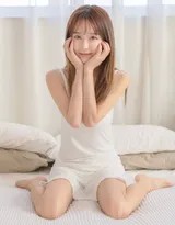 小九身着丝质吊带裙倚靠窗边，暖阳透过白纱帘洒落肩头