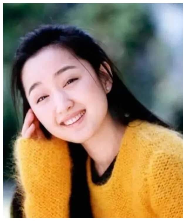 90年代杨钰莹身穿白色连衣裙手持麦克风在舞台上的经典怀旧照